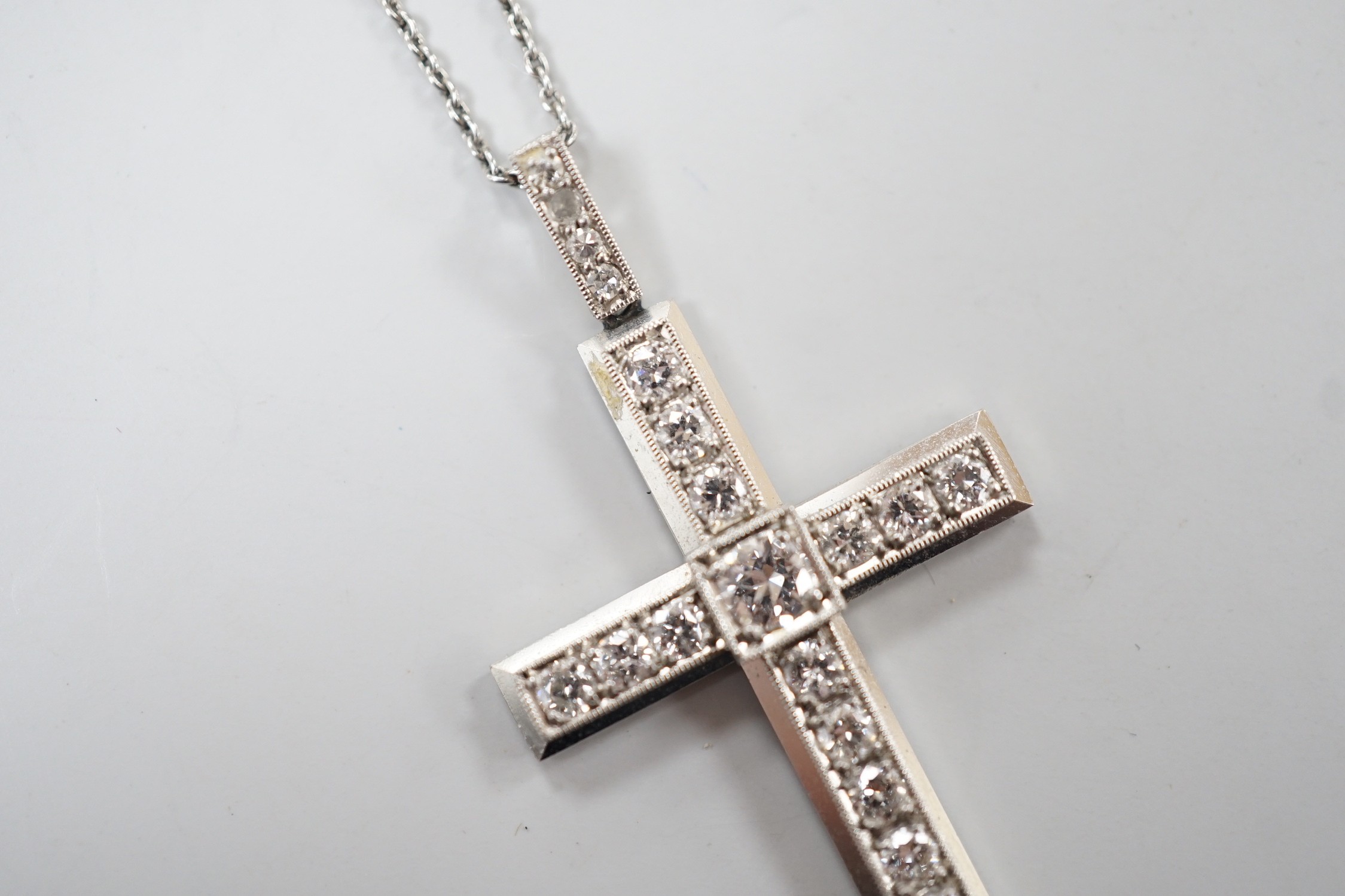A white metal(stamped platin) and diamond set cross pendant, overall 46mm, on a white metal chain, 70cm, gross weight 12.1 grams